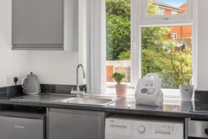 A modern kitchen with a built-in dishwasher, a kettle, and a coffee maker.