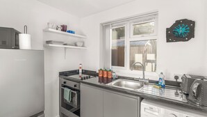 Una cocina moderna con horno empotrado, lavavajillas, pileta y ventana.