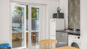 Een kleine keuken met een magnetron, koelkast en wasmachine.