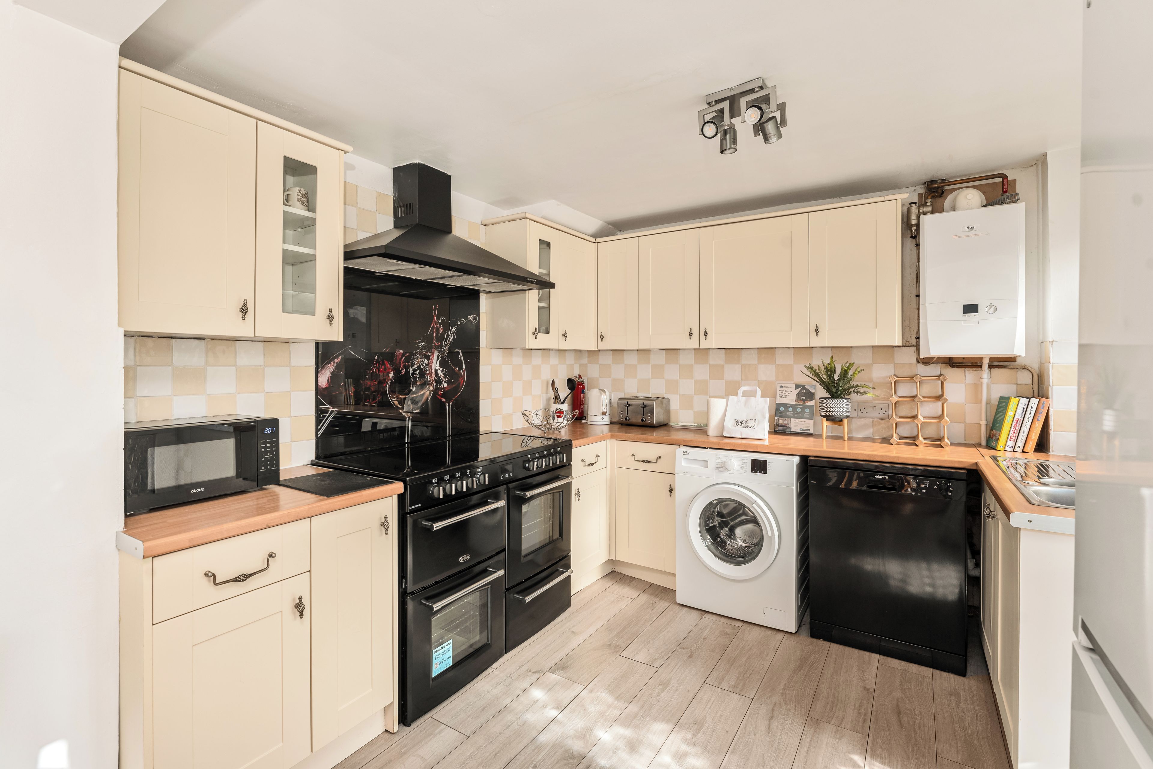 A modern kitchen with a microwave, stove, oven, washing machine, and a water heater.