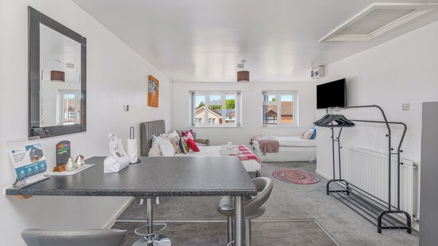 Una habitación de hotel moderna con cama, zona de estar y una kitchenette pequeña.