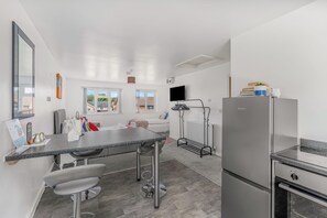 Una cocina moderna con encimera de granito, electrodomésticos de acero inoxidable y una zona de comedor con taburetes de bar.