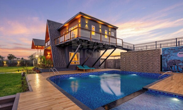 Una casa moderna con piscina, terraza y vista al atardecer.