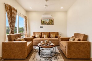 A living room with a sofa set, a coffee table, and a painting on the wall.