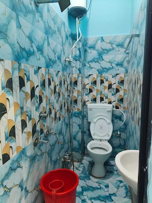 A bathroom with a toilet, bidet, and sink, featuring blue and white marble tiles with a leaf pattern.