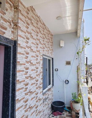 A building with a brick facade, a window, and a wall-mounted light fixture. - Kavya Homestay  (Ujjain)