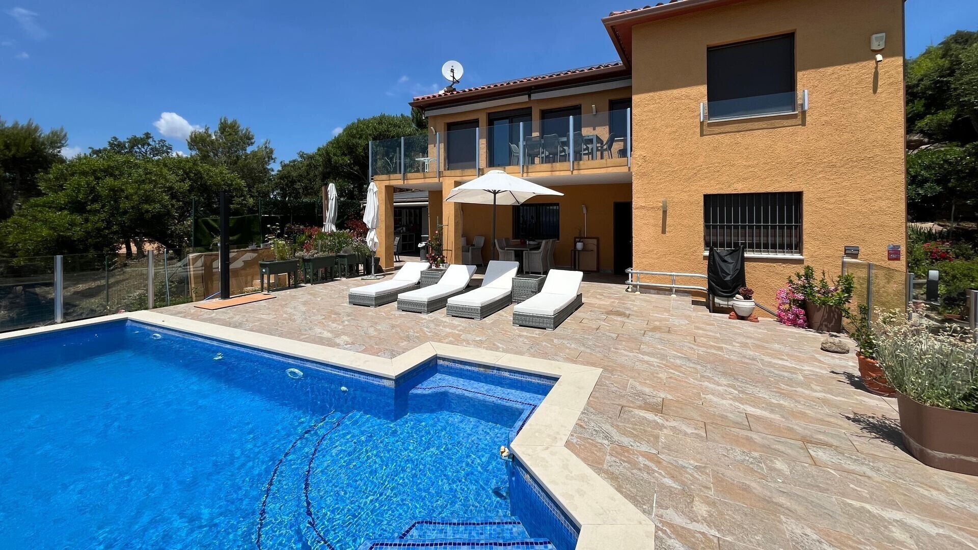 Une maison à deux étages avec une piscine, un espace salon extérieur et un jardin.