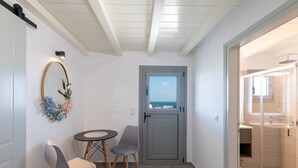 A room with a view, a door, a table, two chairs, and a decorative wall piece. - Paros Golden Beach flats Casa Costa Azor - 33m from beach, sleeps 6 (3BDR 2BA) (Paros)