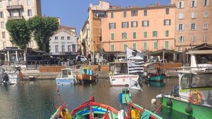 Un bateau aux couleurs vives était amarré dans une marina, avec des bâtiments en arrière-plan.