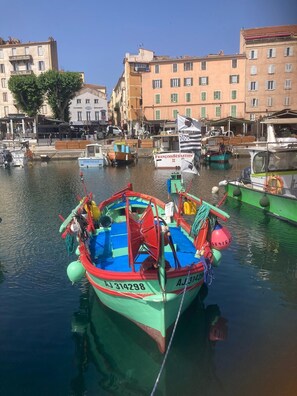 Ein buntes Boot liegt in einer Marina vor einer Gebäudereihe.
