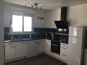 Eine Küche mit weißen Schränken, einem Geschirrspüler, einem Backofen und einem Kühlschrank.