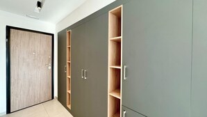Ein Korridor mit einer Holztür, einem grauen Schrank mit mehreren Fächern und einem gefliesten Boden.