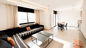 Ein modernes Wohnzimmer mit einer Couch, einem Couchtisch und einem Essbereich mit Stühlen.