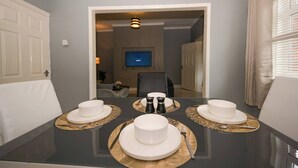 A dining table set with white plates, bowls, and cutlery, with a television in the background. - Spacious Apartment Sleeps 6 Easy Check-in (Gateshead)