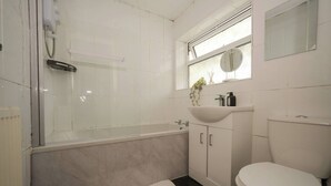 A bathroom with a bathtub, a toilet, a sink, and a window. - Spacious Apartment Sleeps 6 Easy Check-in (Gateshead)