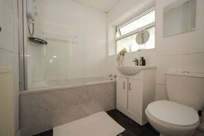 Ein Badezimmer mit Badewanne, Toilette, Waschbecken und einem Fenster.