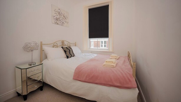 A bedroom with a bed, a bedside table, a window, and a wall-mounted artwork. - Spacious Apartment Sleeps 6 Easy Check-in (Gateshead)