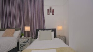 A double bed with two bedside tables, each with a lamp, a large window with curtains, and a wall-mounted artwork. - Spacious Apartment Sleeps 6 Easy Check-in (Gateshead)
