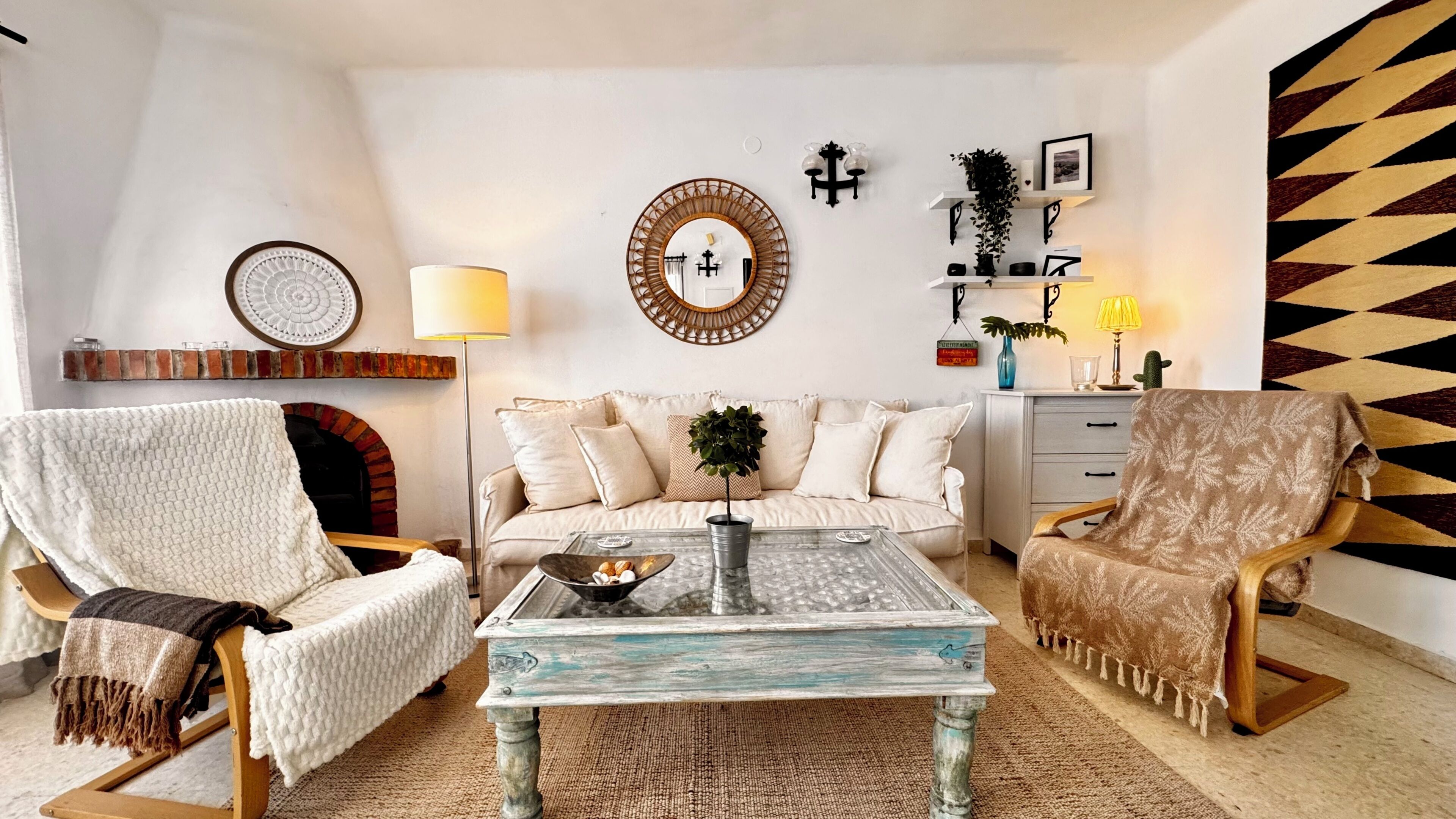 A living room with a fireplace, a sofa, two armchairs, a coffee table, and decorative wall elements.