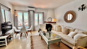 Una sala de estar con sofá, mesa de centro, televisor y comedor.