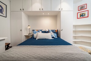 Ein Schlafzimmer mit einem Bett, Nachttischen, einer Lampe und gerahmten Bildern an der Wand.