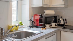 Een keuken met een spoelbak, een koffiezetapparaat, een magnetron en een waterkoker.