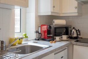Eine Küche mit Spüle, Kaffeemaschine, Mikrowelle und Wasserkocher.