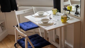 Een eethoek met een witte tafel, blauw gestoffeerde stoelen en een raam met uitzicht.