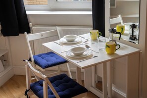 Ein Essbereich mit einem weißen Tisch, blauen Sitzgelegenheiten und einem Fenster mit Aussicht.