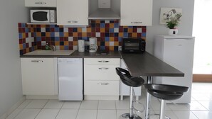 Una cocina moderna con armarios blancos, microondas, cafetera, tostadora y lavavajillas.