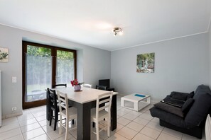 A modern living room with a dining area, a sofa, and a TV.
