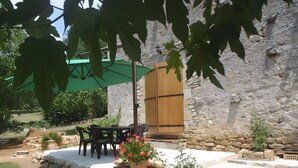 Un patio al aire libre con piso de piedra, una puerta de madera y un paraguas verde.