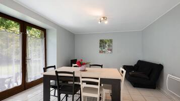 Un comedor con una mesa, sillas, un sofá negro y un cuadro en la pared.
