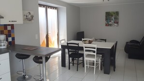 Una cocina moderna con armarios blancos, una mesa de comedor con sillas, una cafetera y un sofá negro.