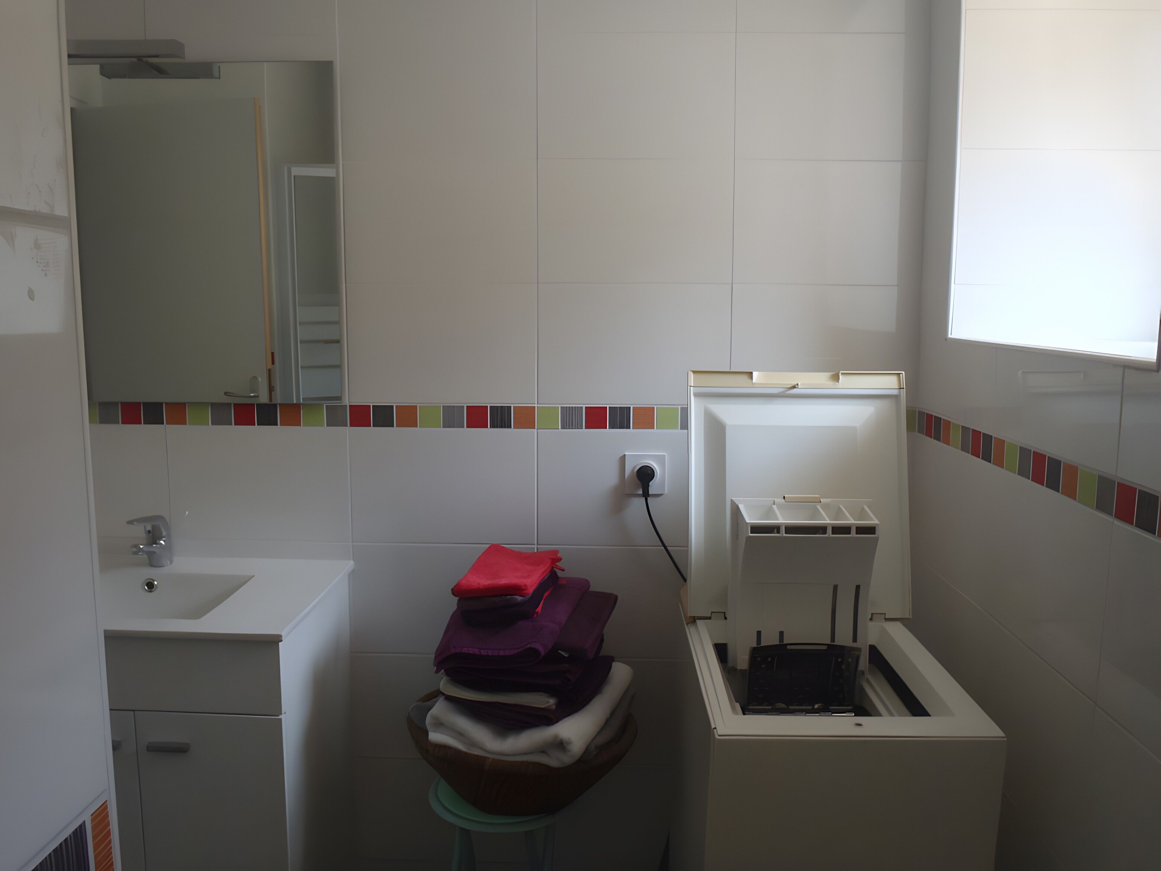 Un baño con lavamanos, espejo, inodoro y un ventanal pequeño.