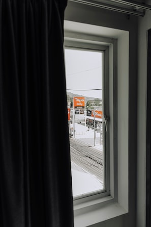 Una ventana con vista a una estación de tren y un letrero de 'Tops Daily' que indica servicio las 24 horas.