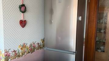 A kitchen with a refrigerator, a patterned wall, and a floral arrangement on the counter.