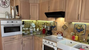 A kitchen with wooden cabinets, two ovens, a sink, and various kitchen utensils. - Vacation Apartment in a Country House in a Quiet Setting in the Elm-Lappwald Recreation Area (Frellstedt)