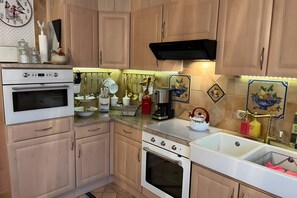 Una cocina con armarios de madera, dos hornos, un lavabo y diversos utensilios de cocina.