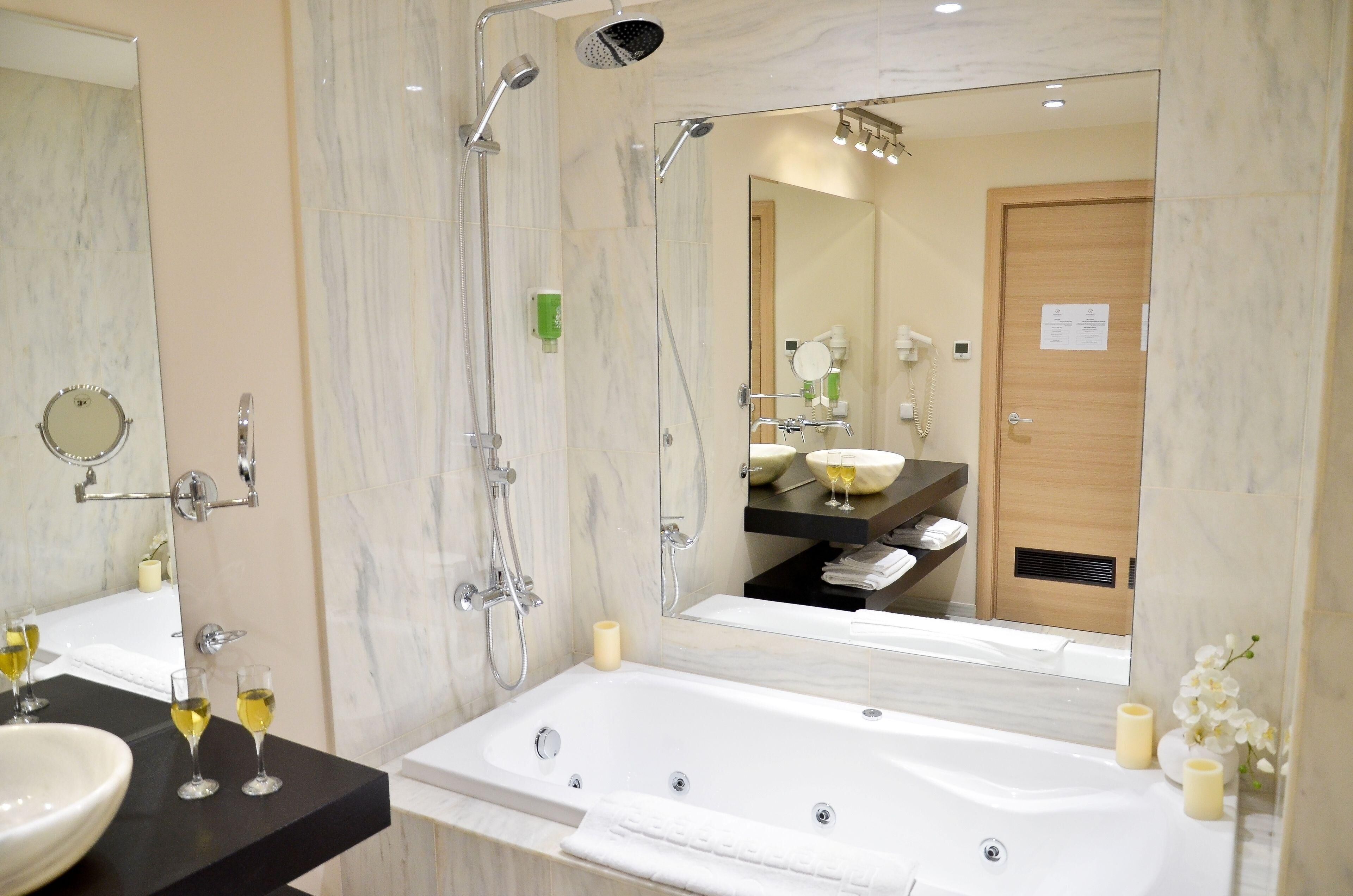 Un baño moderno con bañera, un espejo grande y un tocador con lavabo.