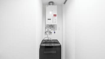 A white wall with a water heater and a black appliance, possibly a washer or dryer, in a corner.