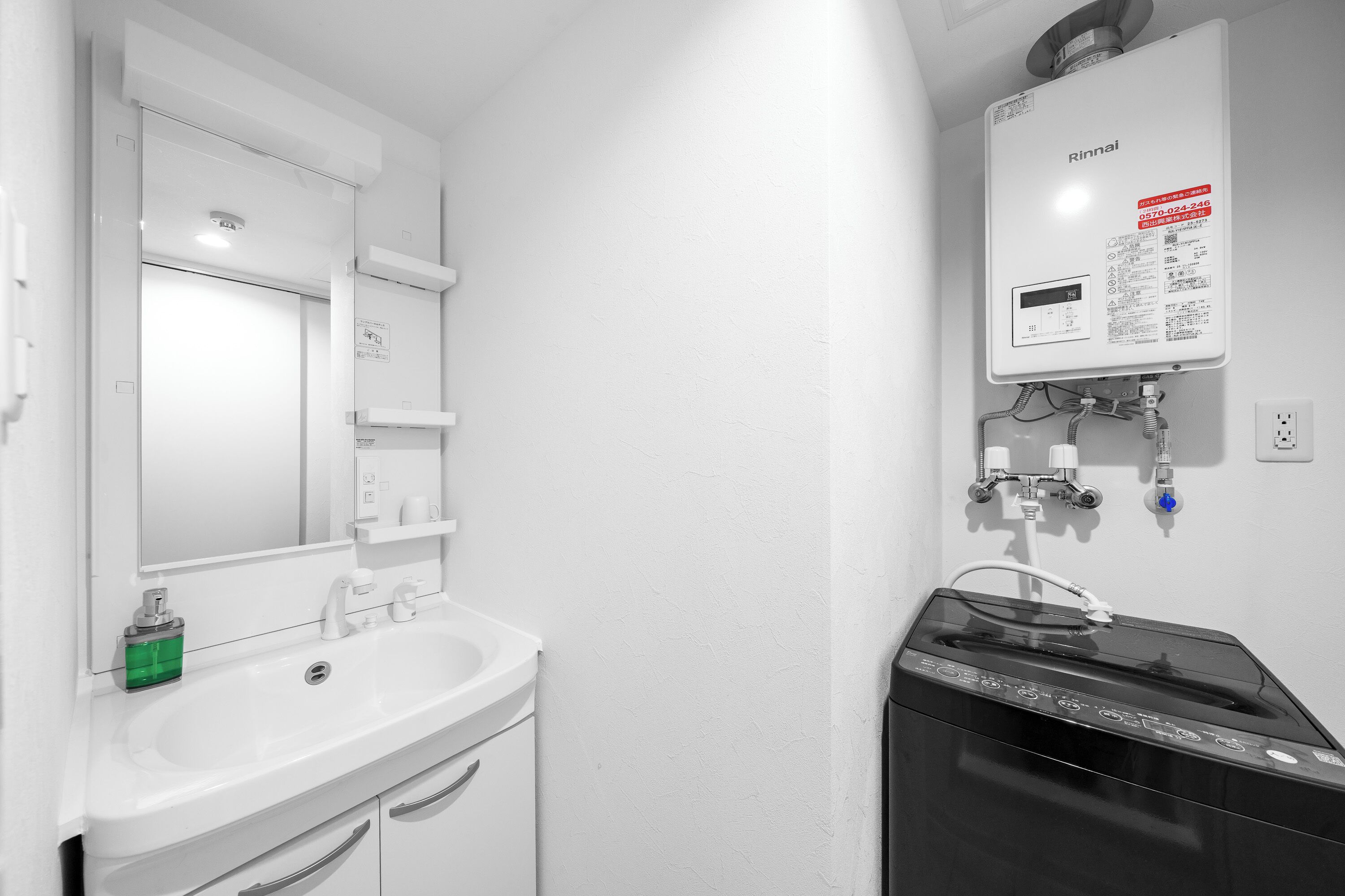 A bathroom with a white sink, mirror, and a black water heater.