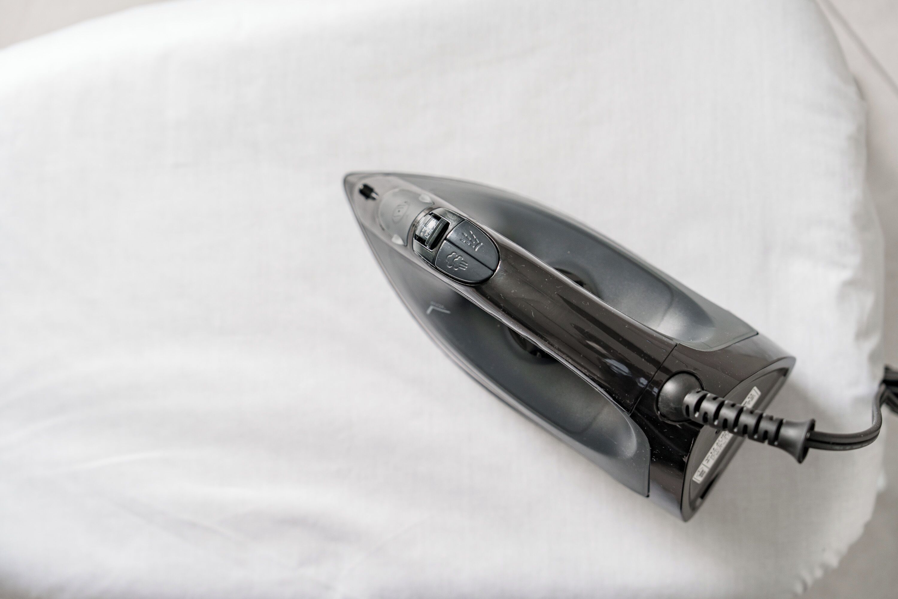 A modern iron on a white fabric surface.