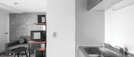 A modern kitchen with a stainless steel sink, a built-in oven, and a grey textured wall.