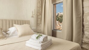 Cama arrumada com vista para a paisagem urbana pela janela.