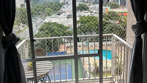 Un balcon avec vue sur le paysage urbain, une piscine et une terrasse en bois.