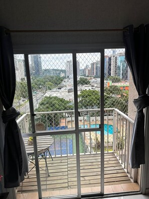 Ein Balkon mit Blick auf eine Stadtlandschaft, einen Pool und eine Holzterrasse.