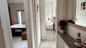 Un couloir avec un lit, une commode et un miroir.