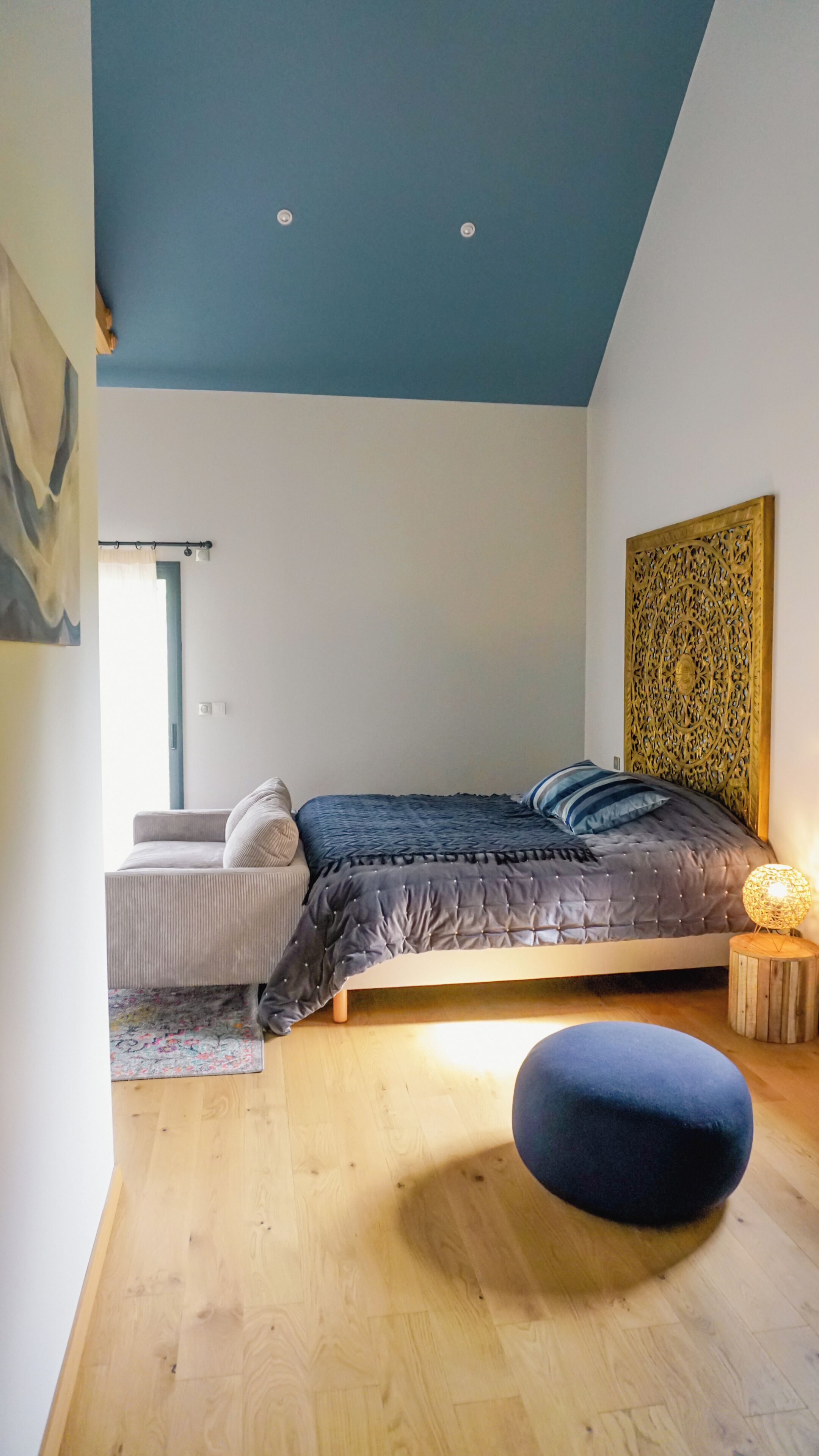 Ein Schlafzimmer mit Bett, einer Bank, einer Wanddekoration und einem Fenster.