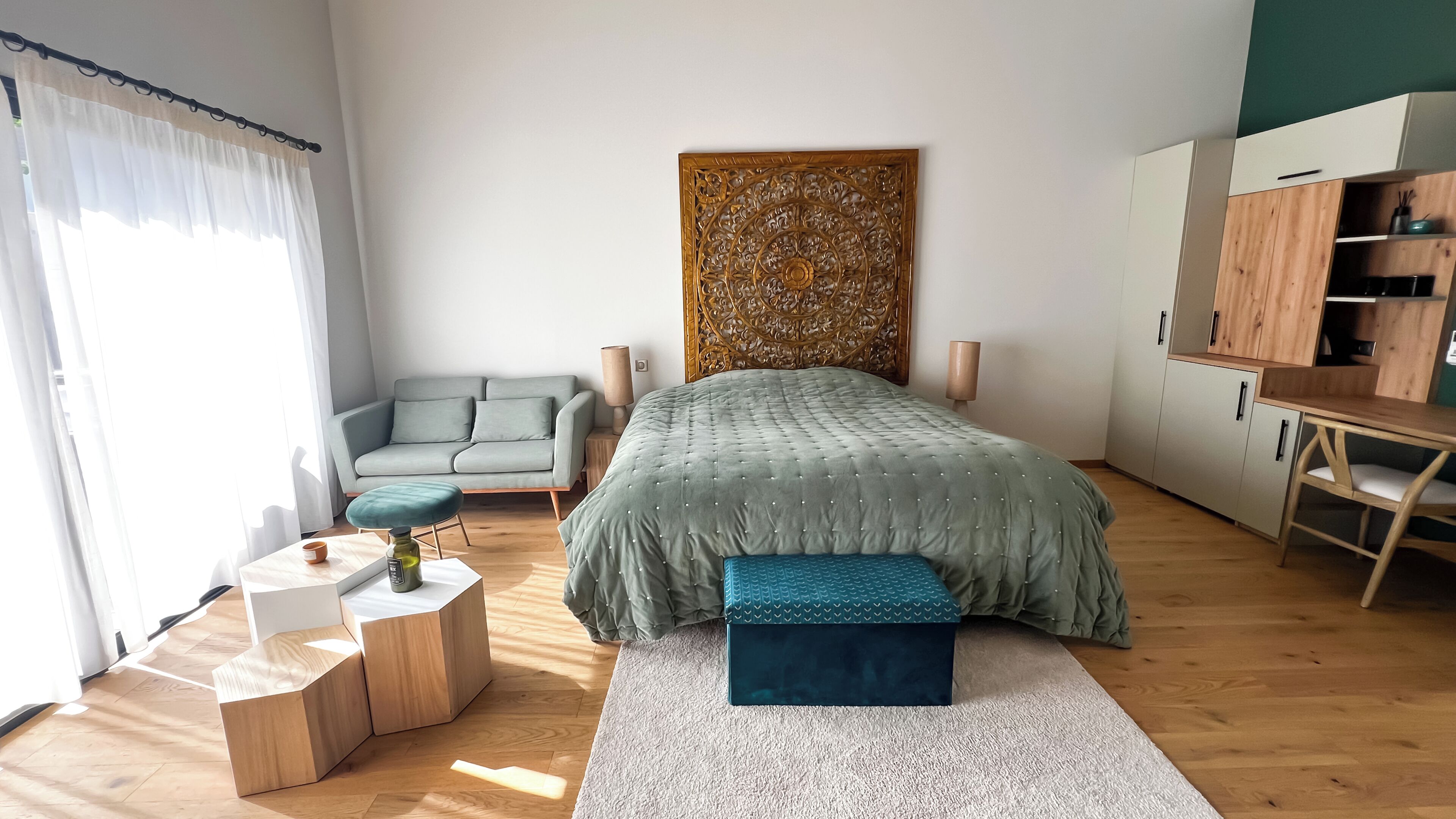 A modern bedroom with a bed, a sofa, a desk, and a wardrobe.